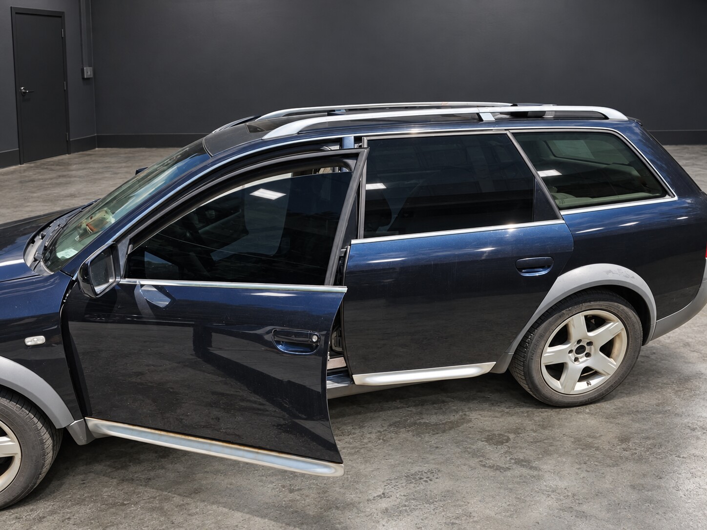 Window tint installation on a dark blue wagon